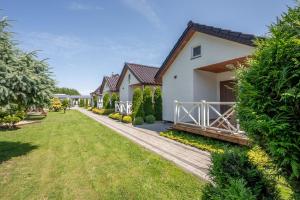 a house with a wooden walkway in front of a yard at Białe Żagle - domki nad morzem in Kopań