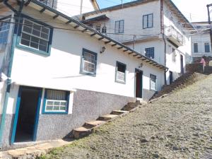 Casa blanca con puertas y escaleras azules en Suíte Aconchegante em Hospedaria no Centro en Ouro Preto