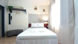 Suíte Charmosa em Hospedaria no Centro في أورو بريتو: غرفة نوم مع سرير أبيض كبير في غرفة