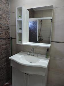 La salle de bains est pourvue d'un lavabo blanc et d'un miroir. dans l'établissement Departamento Confortable, à Puerto Iguazú