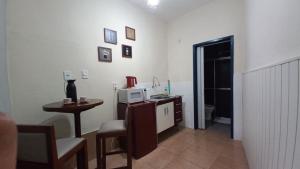 um quarto com uma secretária, um micro-ondas e uma mesa em Suíte Charmosa em Hospedaria no Centro em Ouro Preto