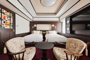 a hotel room with two beds and a table and chairs at Richmond Hotel Nagasaki Shianbashi in Nagasaki