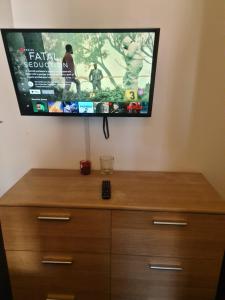 a flat screen tv hanging on a wall above a dresser at D Merciful Homes in Kent