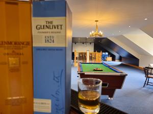 a glass of beer sitting next to a table with a pool at Gleann Fia House in Arrochar
