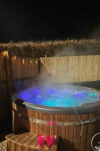 a hot tub with pink shoes in a wooden barrel at Annexe Lodge cottage in Drymen in Drymen