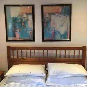 1 cama con 2 almohadas y 2 cuadros en la pared en Annexe Lodge cottage in Drymen, en Drymen