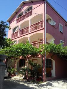 um edifício cor-de-rosa com varandas ao lado em Apartments Zara em Zadar
