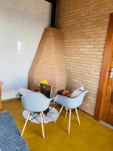 duas cadeiras brancas num quarto com uma parede de tijolos em Chalés Terras Altas em Gonçalves