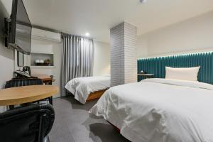 ソウルにあるHotel Chloeのベッド2台とテーブルが備わるホテルルームです。