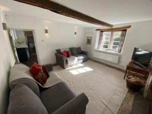 a living room with a couch and a tv at Bridgefoot Cottage in Froggatt