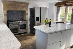 a kitchen with a stove and a counter with yellow flowers at Bridgefoot Cottage in Froggatt