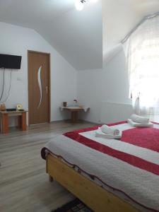 1 dormitorio con 1 cama con manta roja y blanca en Pensiunea Gură de Rai, Pojorâta, en Pojorîta