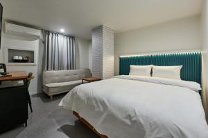 a bedroom with a large white bed and a couch at Hotel Chloe in Seoul