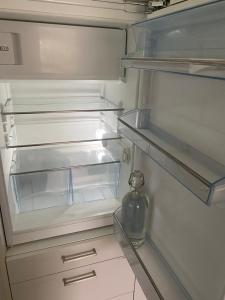 - un réfrigérateur vide avec une porte ouverte et une bouteille dans l'établissement Aux Grands-Vergers, à Bruson