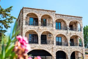 スパタにあるStone Palace Hotel Near Athen's Airport Free Shuttle From and to Athen's Airportの窓とバルコニー付きの古い石造りの建物
