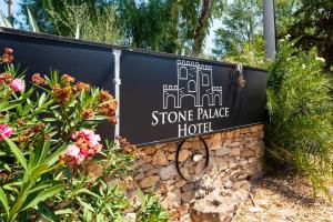 una señal para un hotel de piedra con flores en Stone Palace Hotel Free Shuttle From and to Athen's Airport, en Spáta