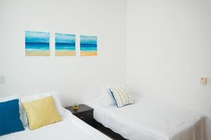 ein Schlafzimmer mit zwei Betten und einem Gemälde an der Wand in der Unterkunft Mágico Apartamento Frente al Mar 3 Habitaciones PV82 in Coveñas + 13 Fotos