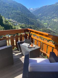 a deck with chairs and tables on a balcony with mountains at Le Preyet in Veysonnaz