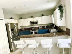 a kitchen with white cabinets and white stools at Comfortable New Home Miami in Tamiami
