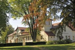 una grande casa bianca seduta in cima a un rigoglioso campo verde di Hotel Frederiksminde a Præstø