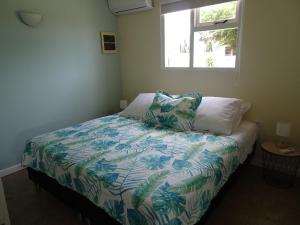 a bedroom with a bed with a colorful comforter and a window at Pura Vida Aruba appartement Cama in Noord