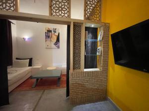 ein Wohnzimmer mit einem Sofa und einem TV in der Unterkunft Riad Samarine in Marrakesch