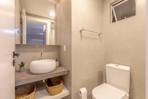 y baño con aseo blanco y lavamanos. en Apartamento Balneario Camboriu Quadra Mar, en Balneário Camboriú