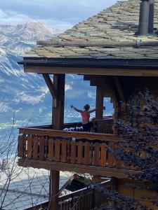 a woman standing on the balcony of a wooden house at Le Preyet in Veysonnaz