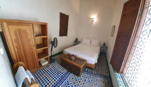 um pequeno quarto com uma cama e uma mesa em Dar Houdou em Fez