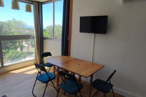 Habitación con mesa de madera con sillas y TV. en Saint Cyprien Sud Méditerranée., en Saint-Cyprien