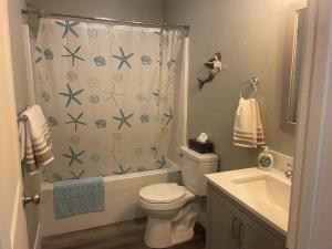 a bathroom with a shower curtain with a toilet and a sink at Puttin Around in Kitty Hawk