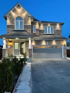 a large house with a garage with a lot at Oshawa Family Haven - Luxury 7BR Villa with Cozy Fireplaces & Hot Tub in Oshawa