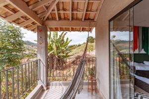 a balcony with a hammock and a view of the ocean at Juiz de Fora, casa linda com piscina, sauna e lareira in Juiz de Fora
