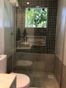 a bathroom with a shower and a toilet and a window at Juiz de Fora, casa linda com piscina, sauna e lareira in Juiz de Fora