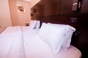 1 dormitorio con 2 camas con sábanas y almohadas blancas en Noble House Hotel en Kumasi