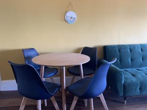 a table with four chairs and a blue couch at Beach View Apartment - Top floor sea view Ramsgate in Ramsgate