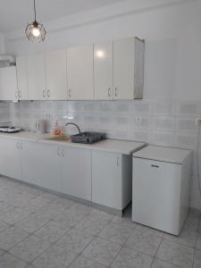 a white kitchen with white cabinets and a sink at PELEKAN rooms and apartments athina 11 in Pefkochori