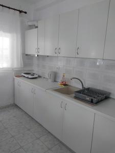 una cucina con mobili bianchi e un lavandino di PELEKAN rooms and apartments athina 11 a Pefkohori Altre 17 foto