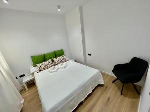 a bedroom with a white bed and a black chair at NEW CAPUCHINOS Apartment 1 in Málaga