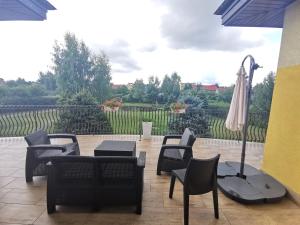 un patio con sillas, una mesa y una sombrilla en Siedlisko nad stawem, en Ełk