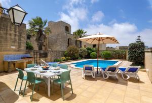 a patio with a table and chairs and an umbrella at Dar ta' Lonza Villa with Private Pool in Għasri