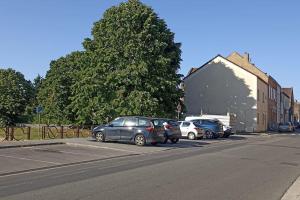 una fila di auto parcheggiate sul lato di una strada di Grand appartement lumineux. a Denain