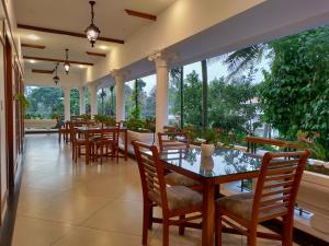 a dining room with tables and chairs and large windows at The Cana's Coorg in Ammatti