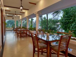 a dining room with tables and chairs and large windows at The Cana's Coorg in Ammatti +30 photos