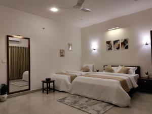 a white bedroom with two beds and a mirror at The Cana's Coorg in Ammatti