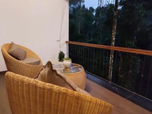 einen Balkon mit Korbstühlen, einem Tisch und einem Fenster in der Unterkunft The Cana's Coorg in Ammatti