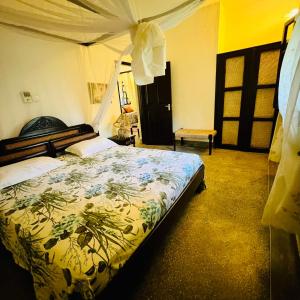 a bedroom with a bed with a floral bedspread at Private cottages @ Karibuni Villas in Malindi