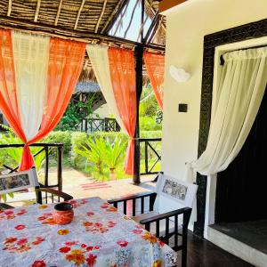 comedor con mesa, sillas y cortinas en Private cottages @ Karibuni Villas en Malindi