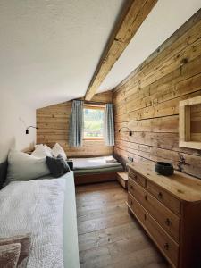 1 dormitorio con 1 cama y pared de madera en Chalet BRUNNHÄUSL, en Hüttschlag