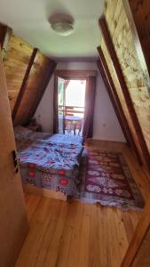 an attic room with a bed and a window at Planinska Kuća Dušan in Mitrovac